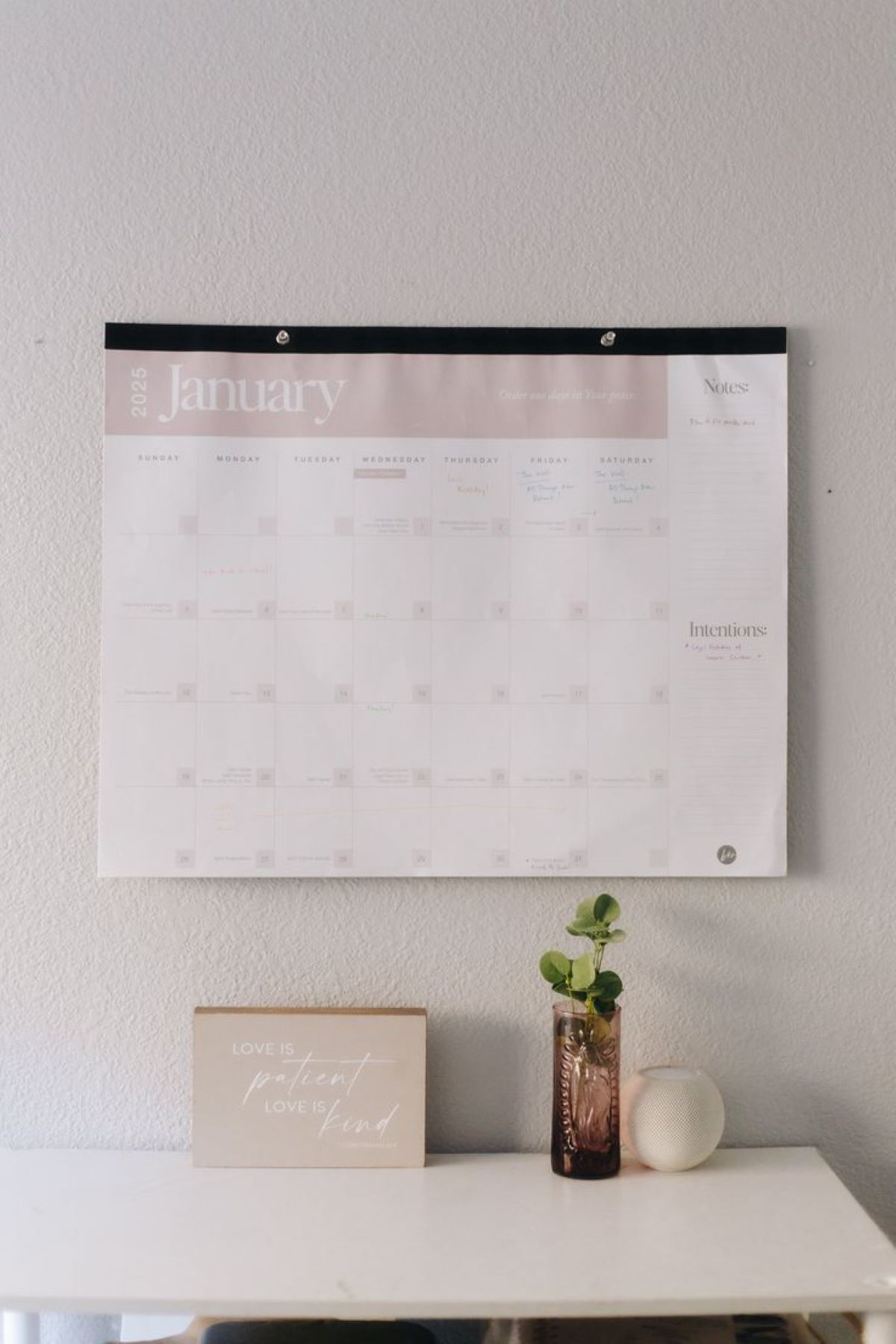 Wall calendar, decorative sign, and vase on a desk in Raleigh, North Carolina.