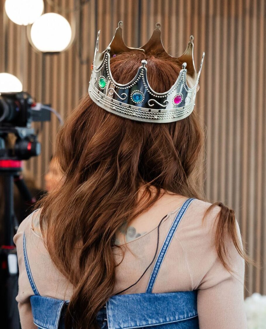 A woman with great extensions wears a gold crown over a custom crown for hair loss